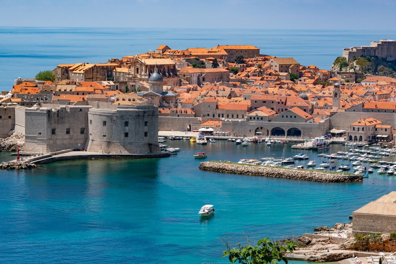 Stunning aerial view of Dubrovnik's historic fortress and marina with vibrant blue waters.