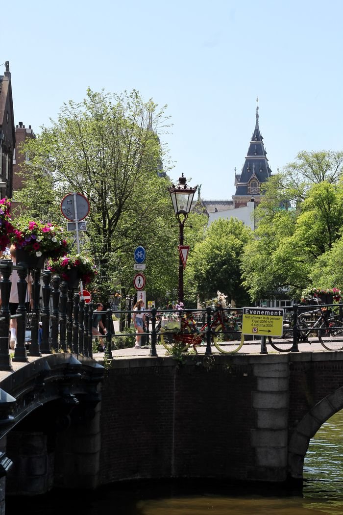A picturesque view of a canal street in Amsterdam, featuring historic architecture and lush greenery.